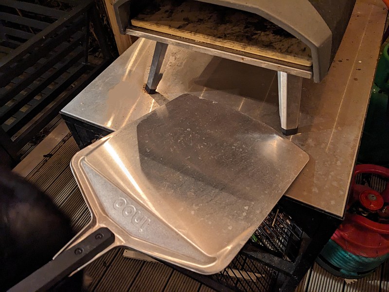 pizza peel next to an ooni pizza oven